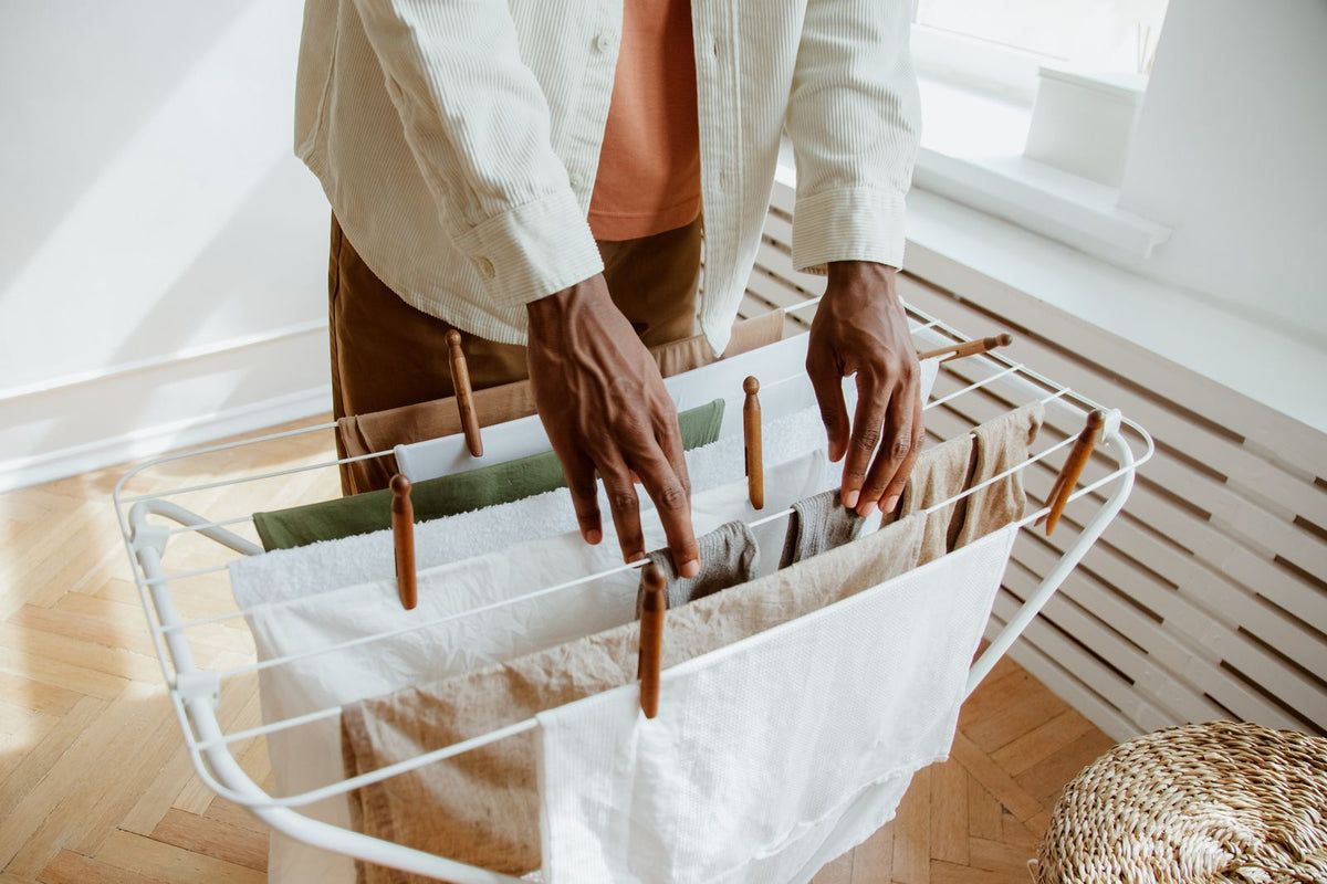 Man hangt schoon wasgoed op een droogrek binnenshuis