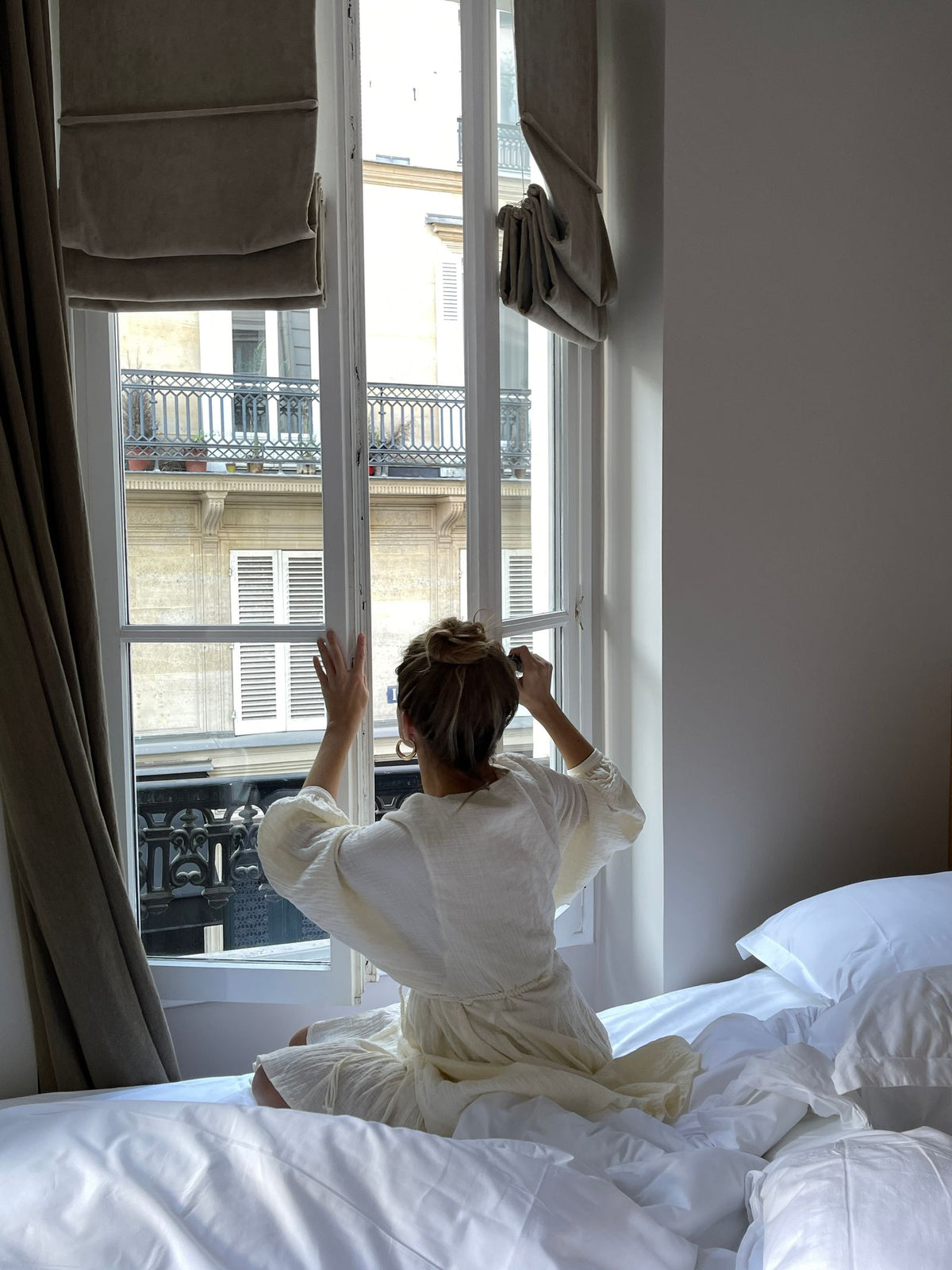 Vrouw die een raam opent in de slaapkamer voor frisse lucht