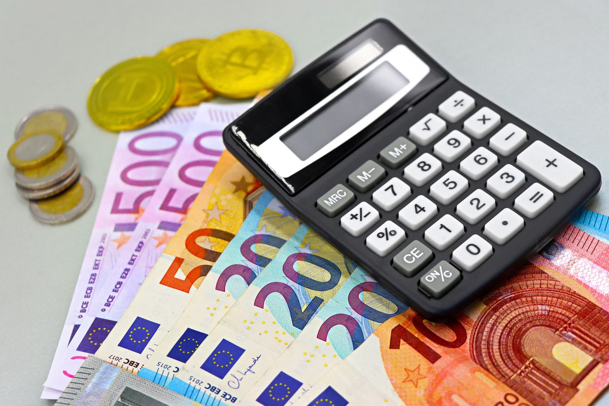 Eurobankbiljetten, muntgeld en een rekenmachine samen op tafel voor een financiele berekening