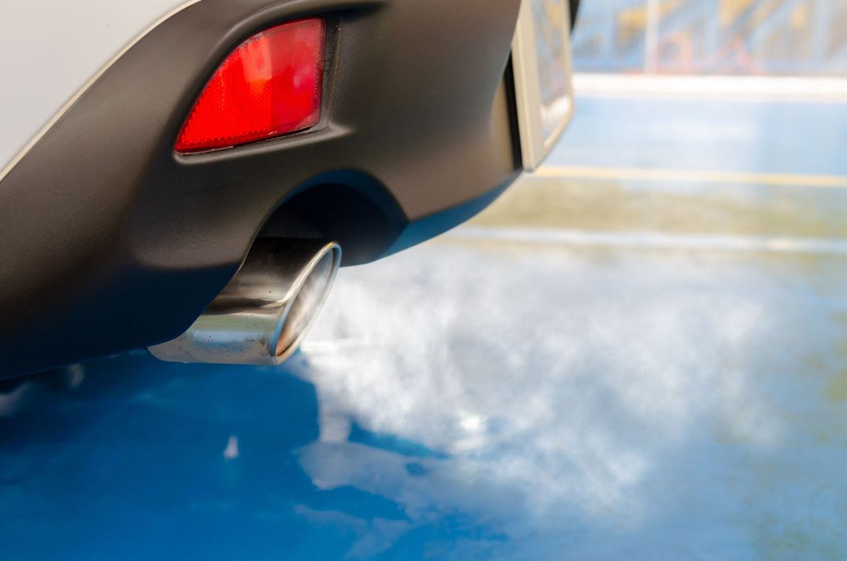 Close-up van een uitlaatpijp van een auto die donkere rook uitstoot