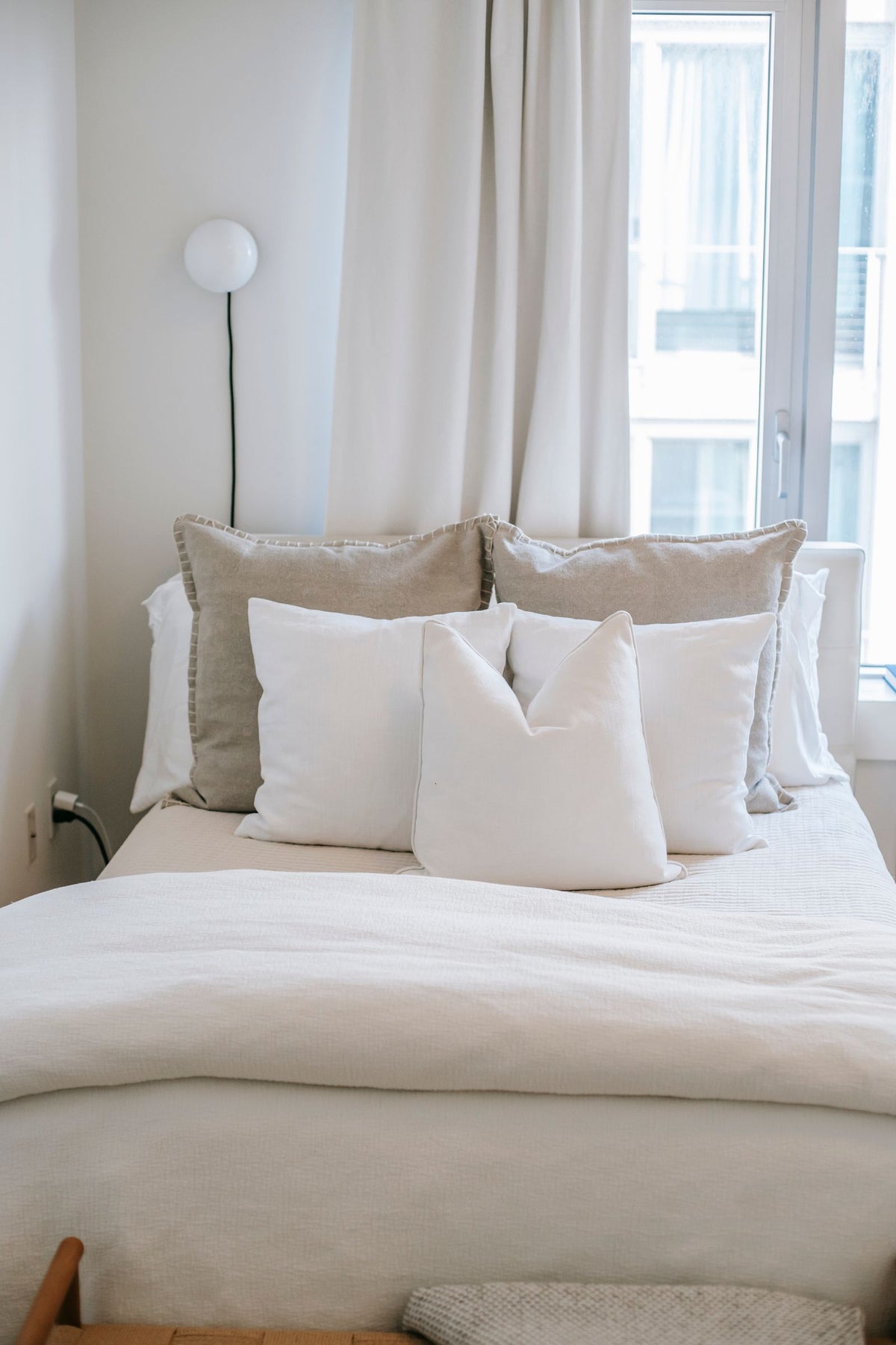Rustige slaapkamer met opgemaakt bed bij het raam, waar een prettige luchtvochtigheid zorgt voor betere nachtrust