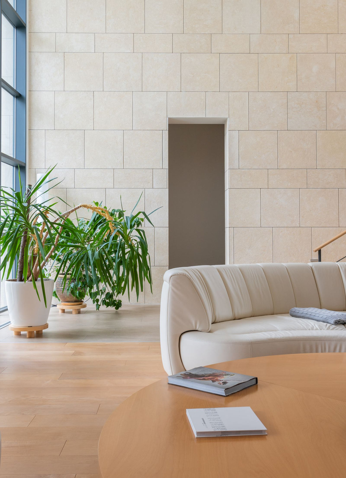 Woonkamer met bank, ronde tafel en planten, met ruime vrije vloerruimte